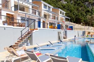 a hotel with a swimming pool with chairs and a building at Sappho Boutique Suites in Vasiliki
