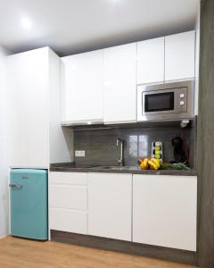kuchnia z białymi szafkami i niebieską lodówką w obiekcie Flamingo Apartment w Maladze +27 zdjęć