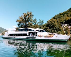 a white boat on the water on a river at Villetta Rosa in Lavena Ponte Tresa