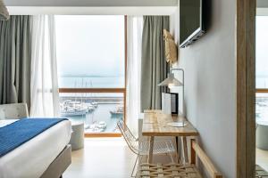 a hotel room with a bed and a desk and a window at Vincci Puertochico in Santander