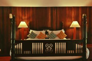 a black bed with pillows on it with two lamps at Spice Village Thekkady - CGH Earth in Thekkady