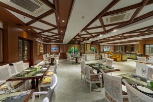 a dining room with tables and white chairs at Mayfair Palm Beach Resort in Gopālpur