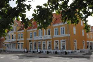 un bâtiment jaune avec des fenêtres blanches et des chaises blanches dans l'établissement Skagen Hotel, à Skagen