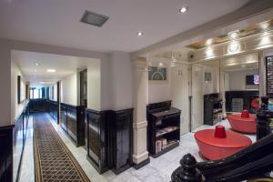 a living room with a fireplace and a red stool at Dutch Masters Short Stay Apartments in Amsterdam