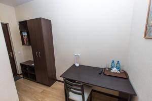 トムスクにあるAsti Rooms Hotelのテーブルとボトル入りキャビネットが備わる客室です。