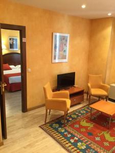 um quarto com uma televisão e duas cadeiras e uma cama em Hotel Cordón em Burgos