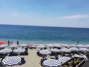 a beach with blue and white umbrellas and the ocean at Albamare in Monterosso al Mare