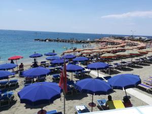 a beach with lots of blue umbrellas and the ocean at Albamare in Monterosso al Mare