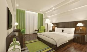 a bedroom with a large bed and a green chair at Regenta Central Hestia Dahej, Bhensali in Dahej +35 photos