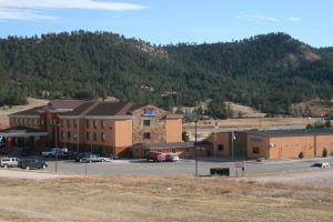 a building with a parking lot in front of a mountain at Stay USA Hotel and Suites in Hot Springs