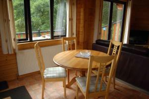 uma mesa de madeira e cadeiras num quarto com janelas em Luxury woodland Alder Lodge em Killin