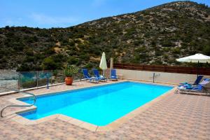 una piscina con sedie e una montagna sullo sfondo di Villa Ocean Breeze a Peyia