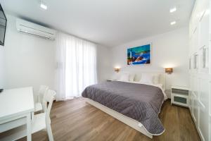 a white bedroom with a bed and a desk at Modern Villa Christian with pool, sauna, and jacuzzi, 10 min walk from the beach in Malinska +28 photos