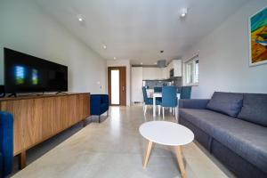 a living room with a couch and a tv and a table at Modern Villa Christian with pool, sauna, and jacuzzi, 10 min walk from the beach in Malinska