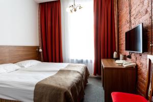 a hotel room with a bed and a desk with a television at Talisman Gorokhovaya in Saint Petersburg