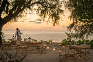 a man standing in front of tables on the beach at Four Seasons Resort Seychelles at Desroches Island in Desroches