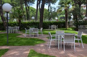 een groep tafels en stoelen in een park bij Hotel Rosen Garden in Milano Marittima