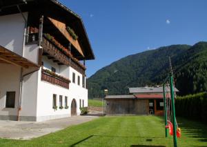 a building with a grass yard in front of a mountain at Watscherhof in Luson