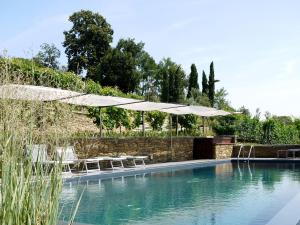 a swimming pool with umbrellas and chairs next to a wall at Residenza la beccata in Pinerolo