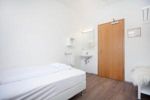 a white room with a bed and a bathroom at Apótek Guesthouse in Akureyri