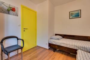 a yellow door in a room with a bed and a chair at Jadrija 6 in Šibenik