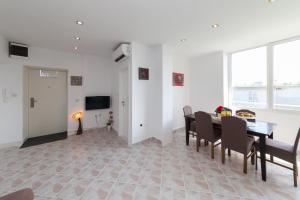 a dining room with a table and chairs and a television at Apartman Bordura in Zadar