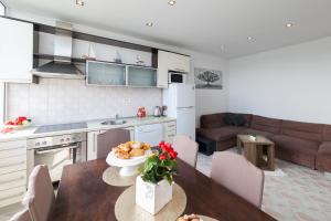 a kitchen and living room with a table and a couch at Apartman Bordura in Zadar