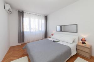 a white bedroom with a bed and a window at Apartman Bordura in Zadar +27 photos