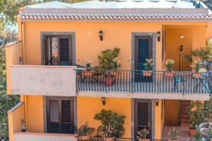 Residence Villa Il Glicine في تاورمينا: منزل برتقالي مع شرفة مع نباتات