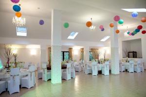 una sala banchetti con tavoli e sedie bianchi e palloncini di BellaVista Brasov a Săcele