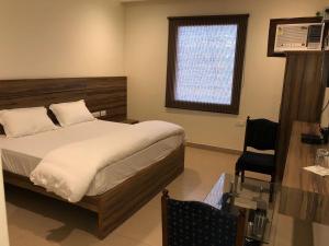 a bedroom with a bed and a window and a chair at Hotel Red Sapphire in Harthala