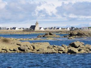 a river with rocks and a church in the background at les volets bleus in Saint-Guénolé