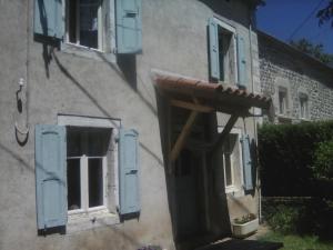 un edificio con ventanas con persianas azules y porche en Gite familial à proximité d'une mini ferme, en Saint-Haon