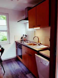 a kitchen with brown cabinets and a sink and a window at Ferienhaus am Badesee Schönsee Bungalow 12 in Urnshausen