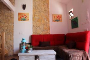a living room with a red couch and a stone wall at Casa Marreiros Holiday Home in Vila do Bispo
