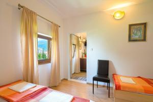 een slaapkamer met 2 bedden, een stoel en een raam bij Astor apartments in Budva