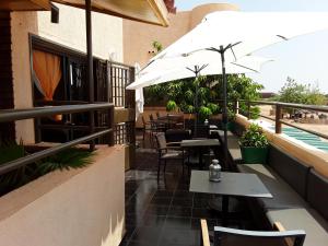 un patio con tavoli, sedie e ombrellone di Le ZaNaLi Hotel a Ouagadougou
