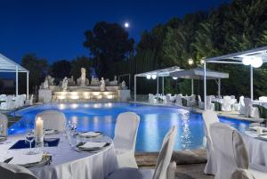 a pool with white tables and chairs in front of it at Grand Hotel Vanvitelli in Caserta