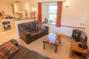 sala de estar con sofá de cuero y mesa de centro en Ballat Smithy Cottage, en Drymen