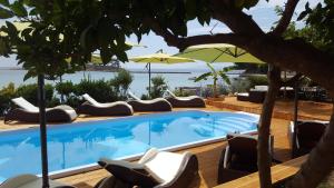 a swimming pool with chairs and an umbrella at Apartment Mare in Rab