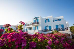 a white building with blue windows and pink flowers at Likio Studios in Batsi