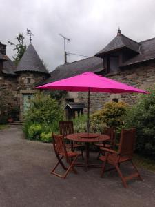 a table and two chairs with a pink umbrella at Le Petit Chateau in Noyal-Pontivy