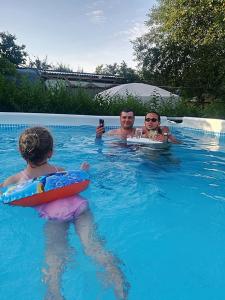 zwei Männer und ein Kind in einem Schwimmbad in der Unterkunft Camping Casuta Mihaela in Crisan