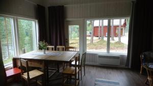 uma sala de jantar com mesa, cadeiras e janelas em Zorbcenter Holiday Homes em Hammarstrand