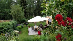 um jardim com um guarda-sol branco, cadeiras e flores em Zum Ehranger Wald 2a em Trier