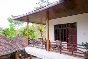 une terrasse couverte d'une maison avec une porte en bois dans l'établissement Matahari Tulamben Guesthouse, à Tulamben
