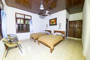 a bedroom with two beds and a table and a chair at Matahari Tulamben Guesthouse in Tulamben