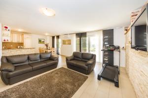 a living room with two leather couches and a flat screen tv at Apartments Orkula in Maslenica