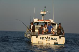 a group of people on a fishing boat in the water at Memmo Baleeira - Design Hotels in Sagres