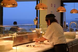 a woman standing in front of a counter filled with cakes at Memmo Baleeira - Design Hotels in Sagres